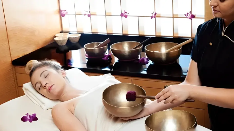 A person receiving a sound therapy session with singing bowls.