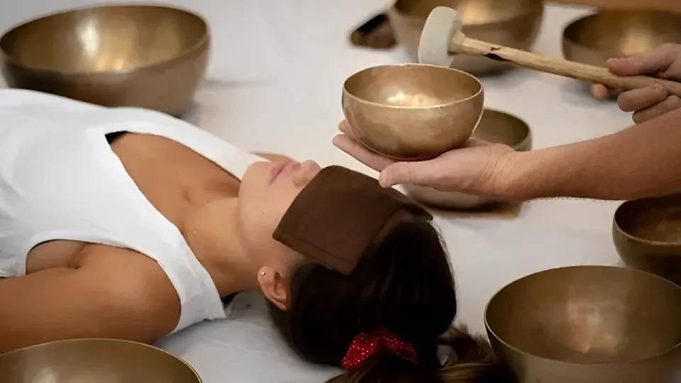 A person receiving a relaxing sound therapy session with singing bowls.