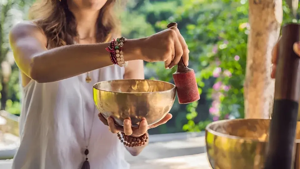 A person playing a singing bowl outdoors.
