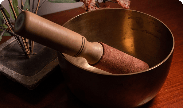 A close-up of a wooden pestle grinding inside a brass mortar bowl.