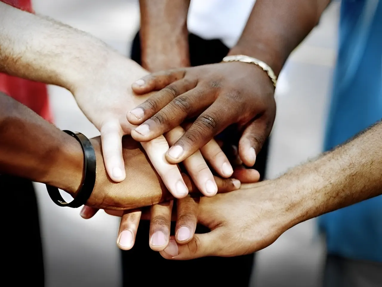 Hands of diverse people stacked together in unity.
