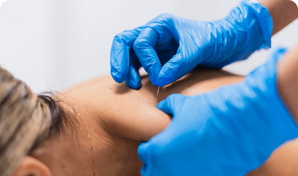 A medical professional wearing blue gloves injecting a needle into a patient's arm.