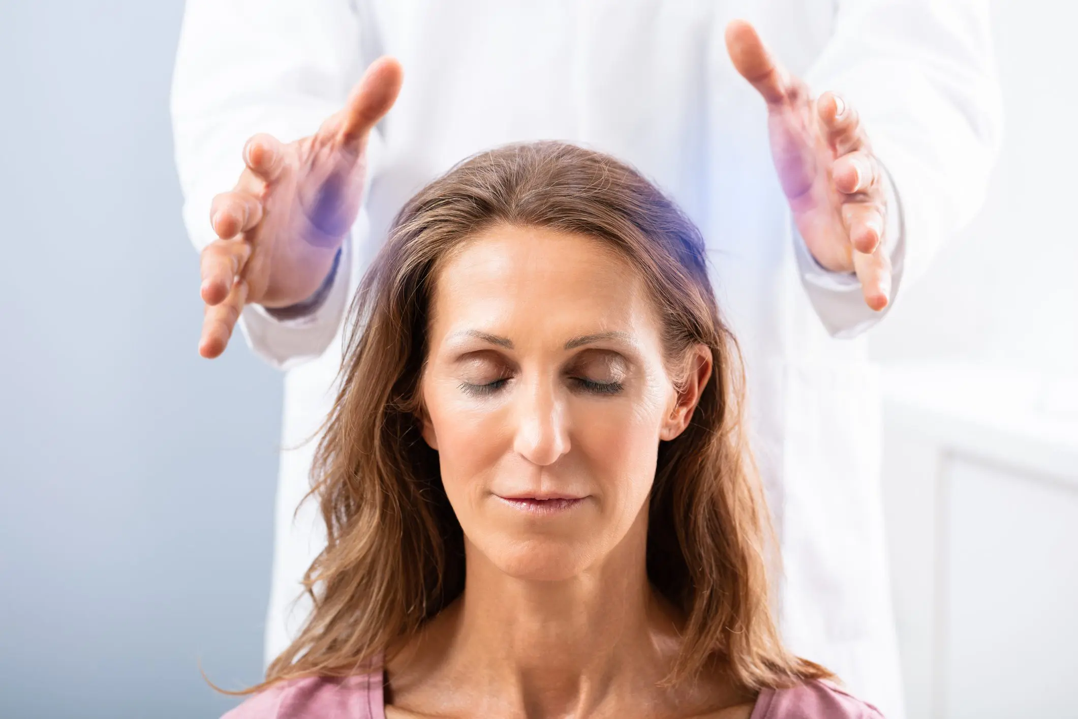 Therapist Giving Reiki Healing Treatment To Woman