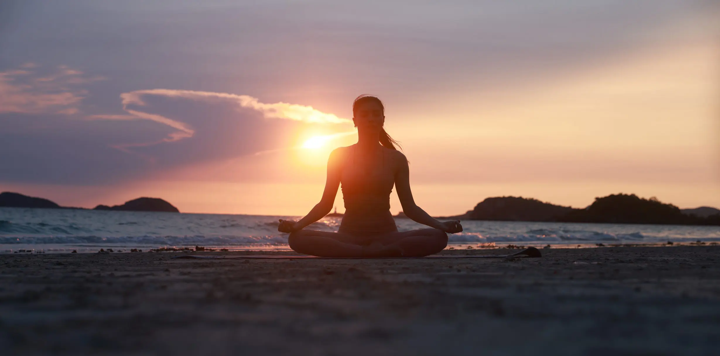 a woman practicing meditation by the beach