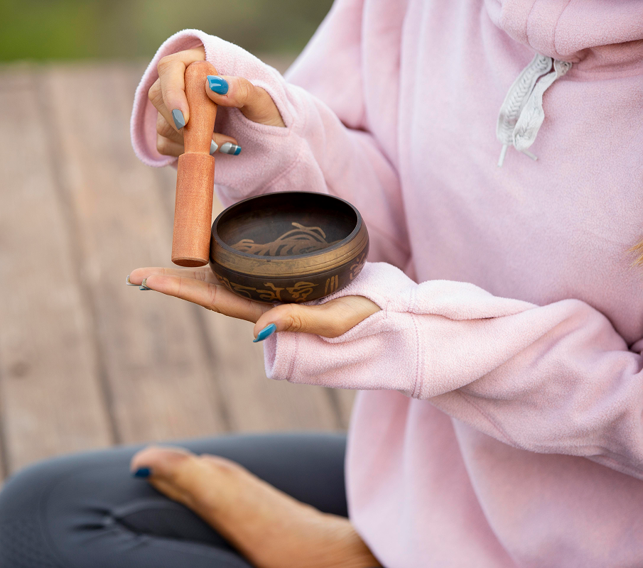 woman-outdoors-holding-singing-bowl 1 A person holding a singing bowl and wooden mallet.