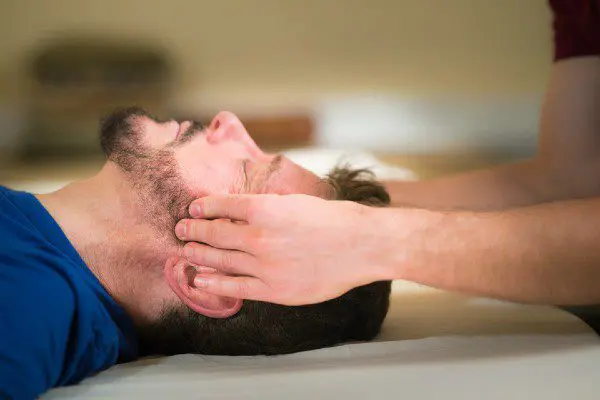 Man receiving gentle head massage on table