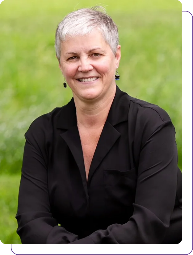 Group 1321317535 (1) Smiling mature woman in a black blazer outdoors.