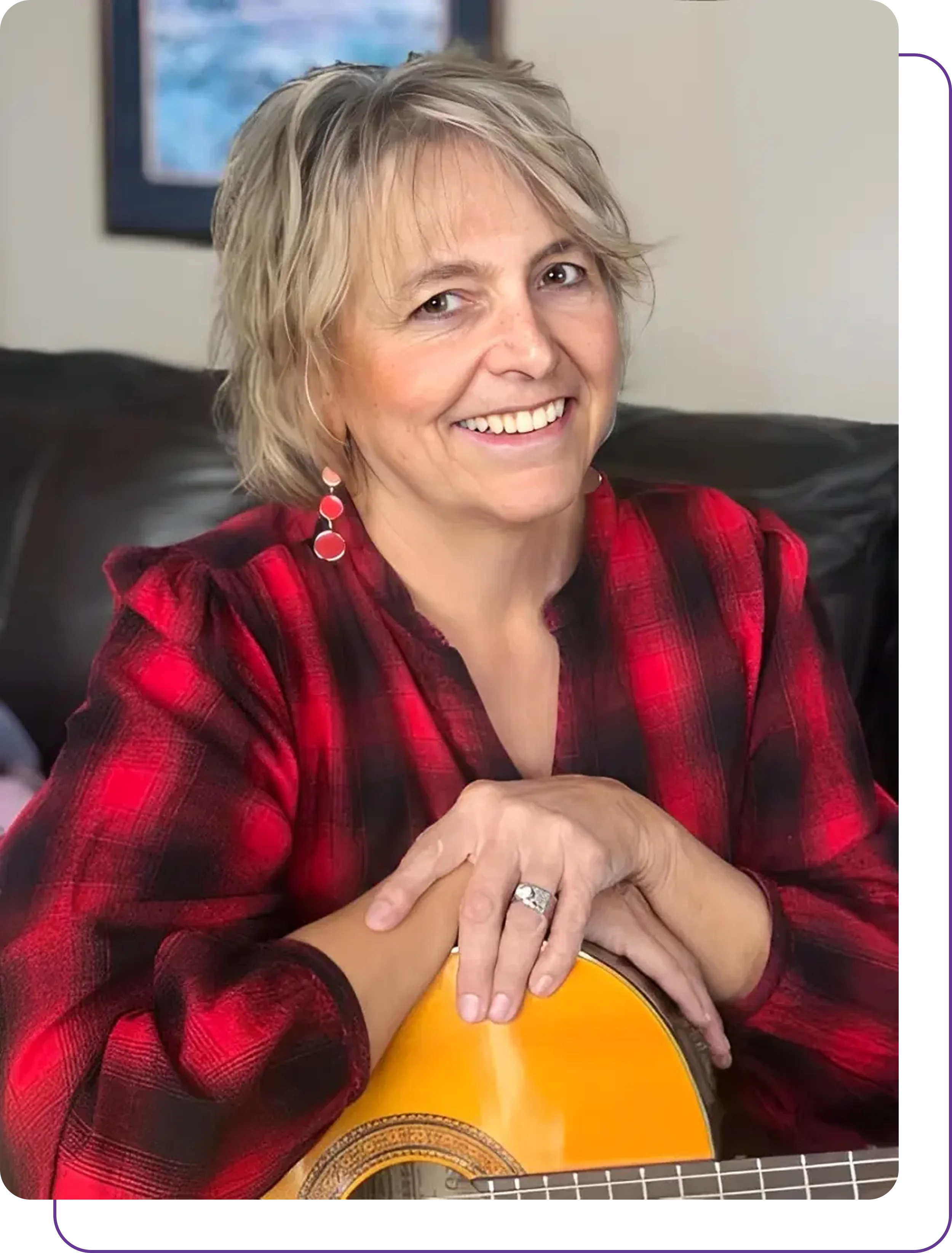 Group 1321317535 Smiling woman in a red plaid shirt sitting on a couch.