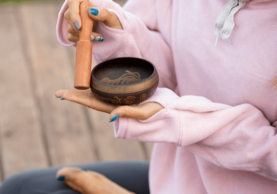 A person holding a singing bowl and wooden mallet.